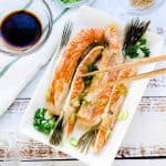Japanese baked salmon belly served on a white plate topped with sesame seeds, top down picture.