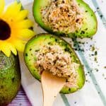 Tuna salad avocado bowl being scooped with a wooden spoon, top down picture.