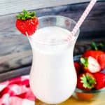 Japanese style strawberry milk smoothie served in a glass cup with a strawberry and a straw, top view shot.