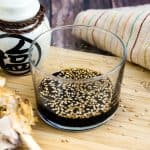 Teriyaki sauce in a cup with sesame seeds on top, side view.