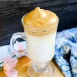Dalgona whipped coffee coconut smoothie served in a glass mug.