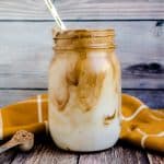 Dalgona mocha coffee served in mason jar with a golden straw.