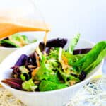 Japanese ginger salad dressing bring poured onto a spring mix salad.