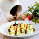 Japanese tonkatsu sauce being poured onto a bed of cabbage.