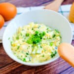 Japanese style Egg Salad served in a white bowl with a wooden spoon, side angle shot.
