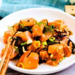 Homemade salmon poke recipe served in a bowl topped with seaweed and fresh chopped green onions, close up shot.