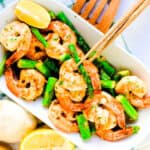 Shrimp asparagus stir fry in garlic butter served on white plate, top down shot.