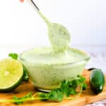 The green sauce being spooned with a spoon.