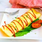 Japanese omelette fried rice severed on a white plate topped with ketchup sauce.