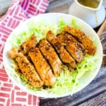 Teriyaki chicken served on a bed of cabbage with sprinkled sesame seeds.