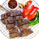 Japanese grilled beef yakiniku served with yakiniku sauce and veggies, top down shot.