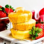 Fluffy Japanese pancakes served on a plate with maple syrup being drizzled on top.