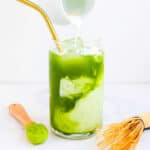 Iced matcha latte served in a glass with milk being poured in.