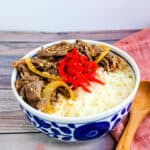 Japanese style beef bowl gyudon served over rice topped with red ginger beni shoga.