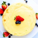 Japanese fluffy cheesecake served on a cake stand with strawberries cut on top, top down shot.