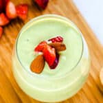 Silken matcha tofu pudding served in a glass cup topped with fresh strawberries and nuts.