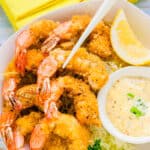 Japanese style fried shrimp served on a bed of shredded cabbage being picked up with a pair of chopsticks.