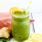 Green strawberry spinach smoothie poured into a cup with a straw.