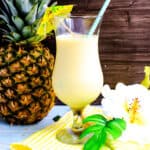 Pina colada served in a glass with a straw and a cocktail umbrella.