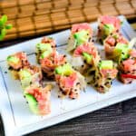 Spicy tuna roll sushi wrapped in soy paper served in on a white plate.