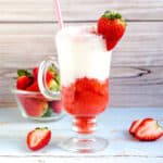 Strawberry cream soda served in a glass with a strawberry on the rim.