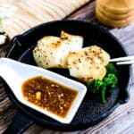 A piece of pan seared cod being dipped into a Japanese style ginger sauce.