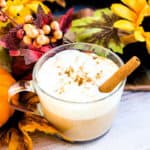 Pumpkin chai latte made with low carb ingredients served in a glass cup topped with pumpkin spice and a cinnamon stick.