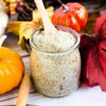 Pumpkin pie chia pudding served in a glass jar with a wooden spoon, side angle.