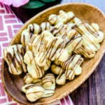 White chocolate covered macadamia nuts dessert snack served in a wooden plate.