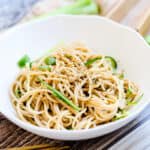 Asian noodle salad served in a bowl with sliced cucumbers and ginger on top.