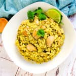 Lime chicken fried rice served in a white bowl with a wedge of lime.