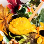 Mashed kabocha salad served in a glass bowl being scooped up with a spoon.