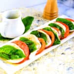 Tomato basil mozzarella bites appetizer dish served on a white plate.