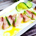 Peruvian style Yellowtail Sashimi Carpaccio Tiradito served on a white plate.