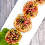 Japanese style tuna tartare served on a fried lotus roots with sesame seeds and shiso leafs.