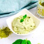 Matcha ice cream made in a mason jar served in a white bowl with mint leaf on top, side shot.