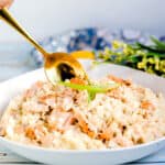 Salmon risotto made served in a white bowl topped with sliced green onions.