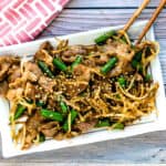 Japanese style pork stir fry served on a plate topped with toasted sesame seeds.