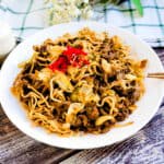 Japanese style stir fry noodles yakisoba served on a plate topped with fresh red ginger beni shoga.