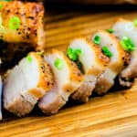 Air fryer pork belly sliced into strips and served on a wooden serving board.