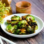 Spicy garlic sautéed brussels sprout in Kung Pao sauce served on a white plate.