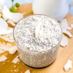 A healthy coconut chia seed pudding dessert served in a glass cup topped with coconut flakes.