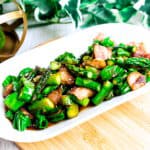 Japanese izakaya style shishito pepper stir fry served on a white plate top down shot.