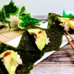 Poor man's sushi made with canned tuna served on seaweed on a white plate.