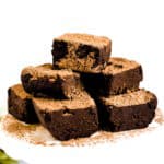 Chocolate truffles served on a white dessert dish with cocoa powder sprinkled on top, side view.