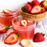 Homemade strawberry jello inside a glass cup with a slice strawberry on top.