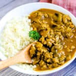 Keema curry served over rice being scooped out with a spoon.