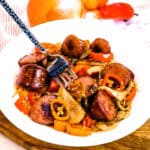 Kielbasa sausage stir fry mixed with vegetables being picked up with a fork.