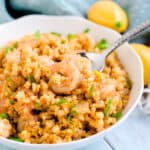 Lemon pepper shrimp cauliflower fried rice being scooped up with a silver spoon.