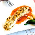 Macadamia crusted halibut with sweet chili sauce topped with freshly chopped parsley, side view.